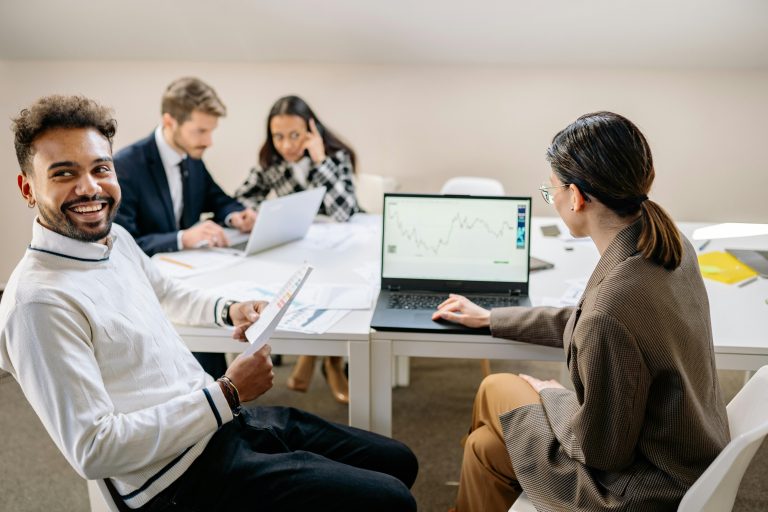 Small business team meeting around a conference table with laptops and documents